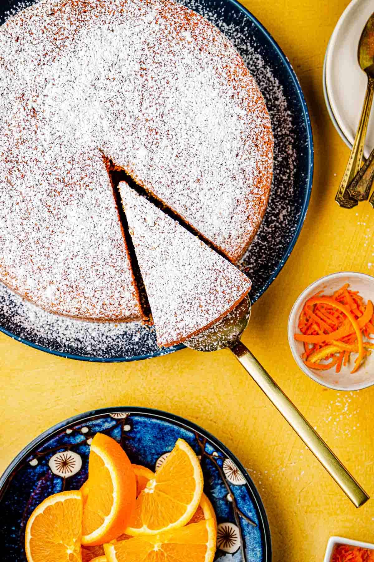 A slice being lifted from a baked Torta di Carote (Italian Carrot Cake) topped with powdered sugar on a plate.