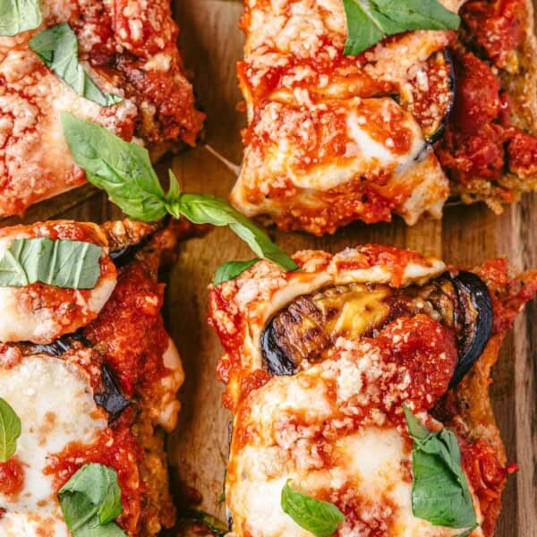 four eggplant parmesan sandwich slices on a serving board.