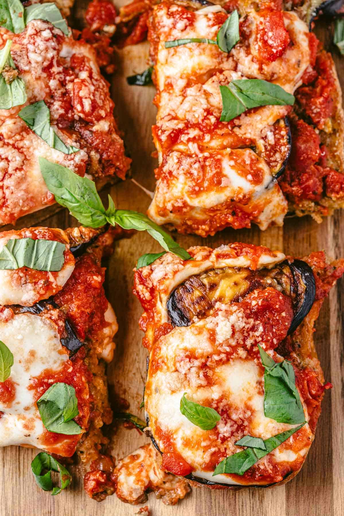 four eggplant parmesan sandwich slices on a serving board.