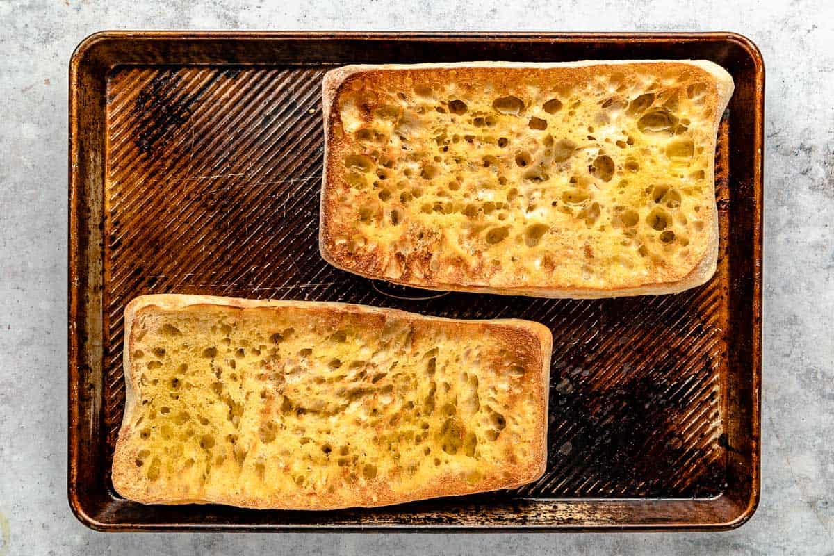moitié grillée de pain ciabatta sur une plaque à pâtisserie.