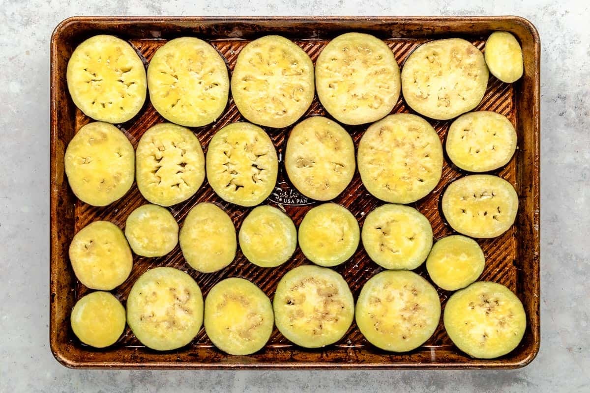 uncooked eggplant slices on a baking sheet.