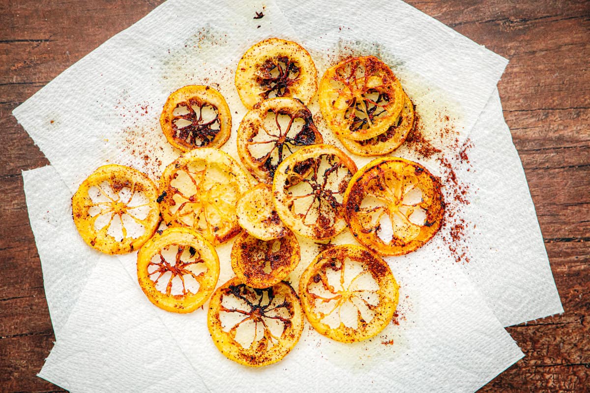 Golden brown and slightly charred lemon rings draining on paper towels.