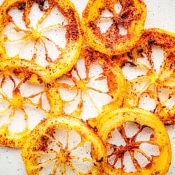 Close up of fried lemon rings with crisp golden brown edges on a white background.