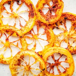 Close up of fried lemon rings with crisp golden brown edges on a white background.