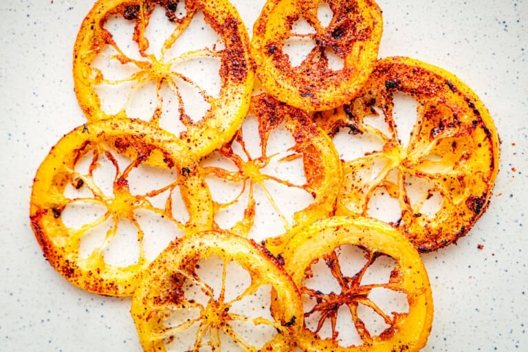 Close up of fried lemon rings with crisp golden brown edges on a white background.