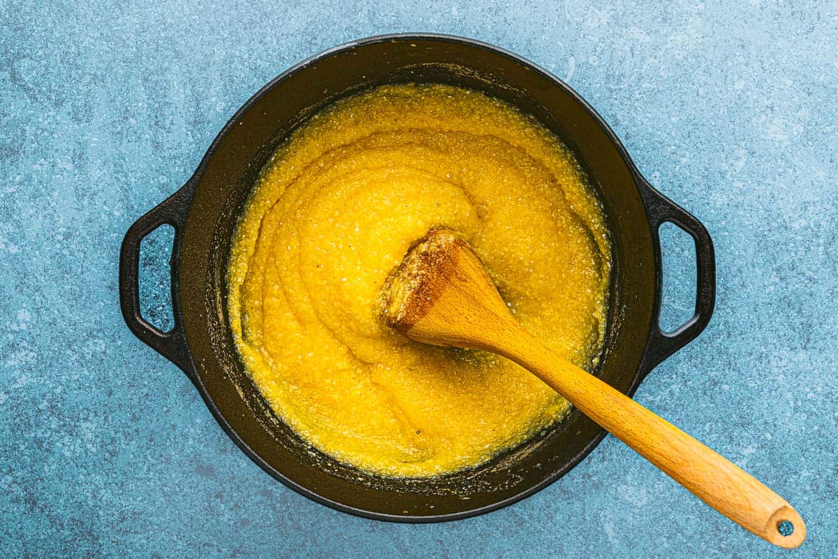 polenta cooking in a pot with a wooden spoon.