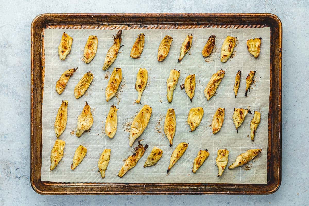 Artichoke hearts that have been spread on a sheet tray and roasted until brown.