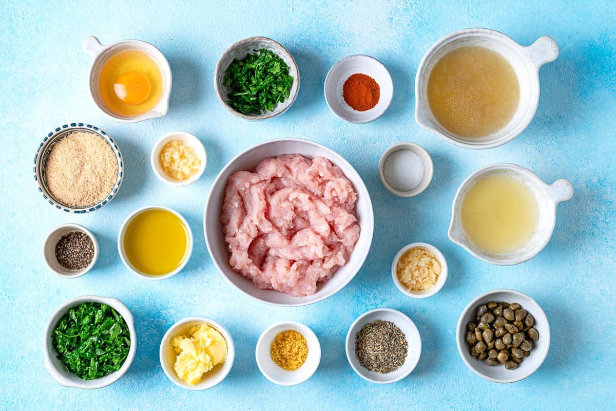 ingredients for chicken piccata meatballs including ground chicken, olive oil, ghee, garlic, lemon juice, lemon zest, white wine, capers, parsley, egg, italian seasoning, paprika, bread crumbs, salt, and pepper.