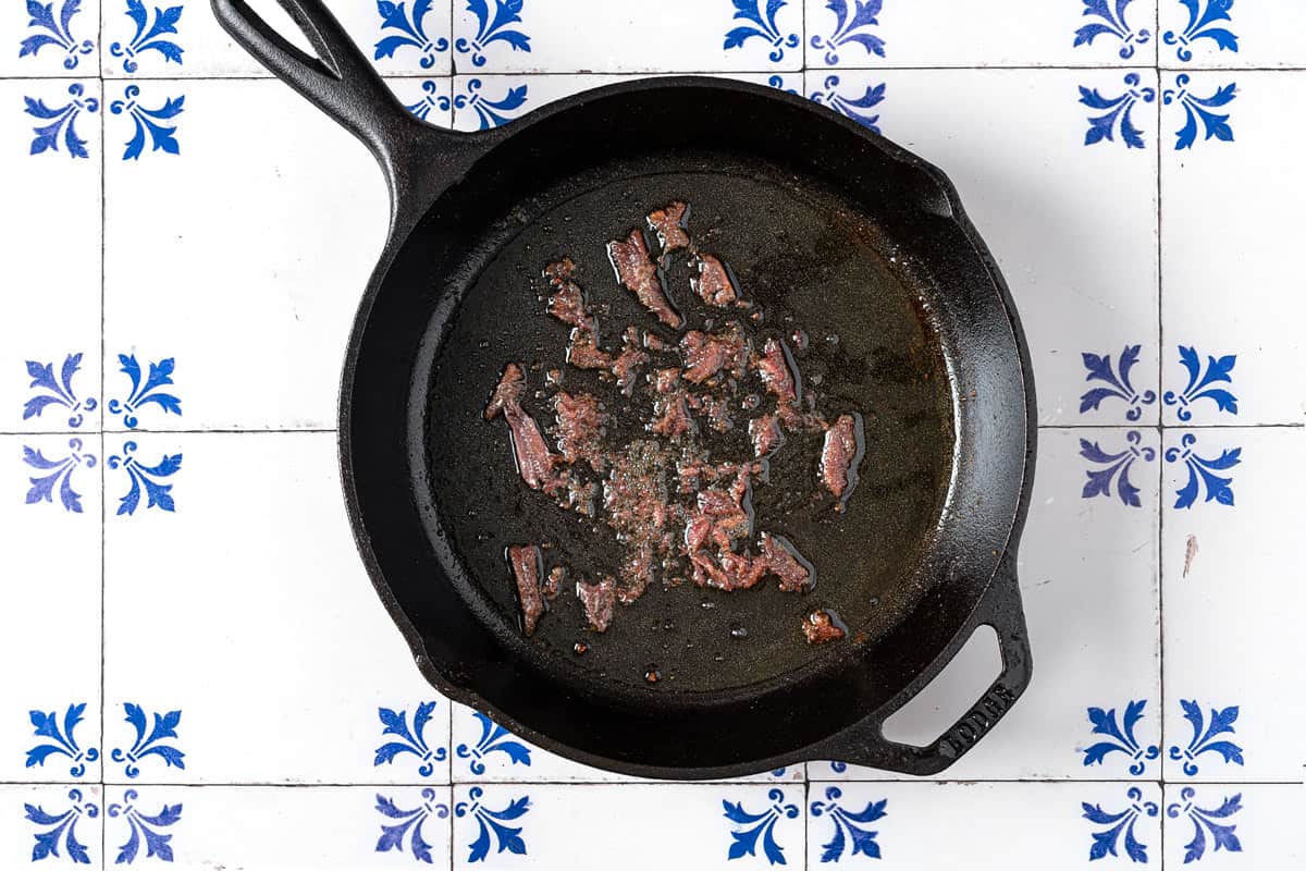 anchovy fillets sauteeing in a cast iron skillet.