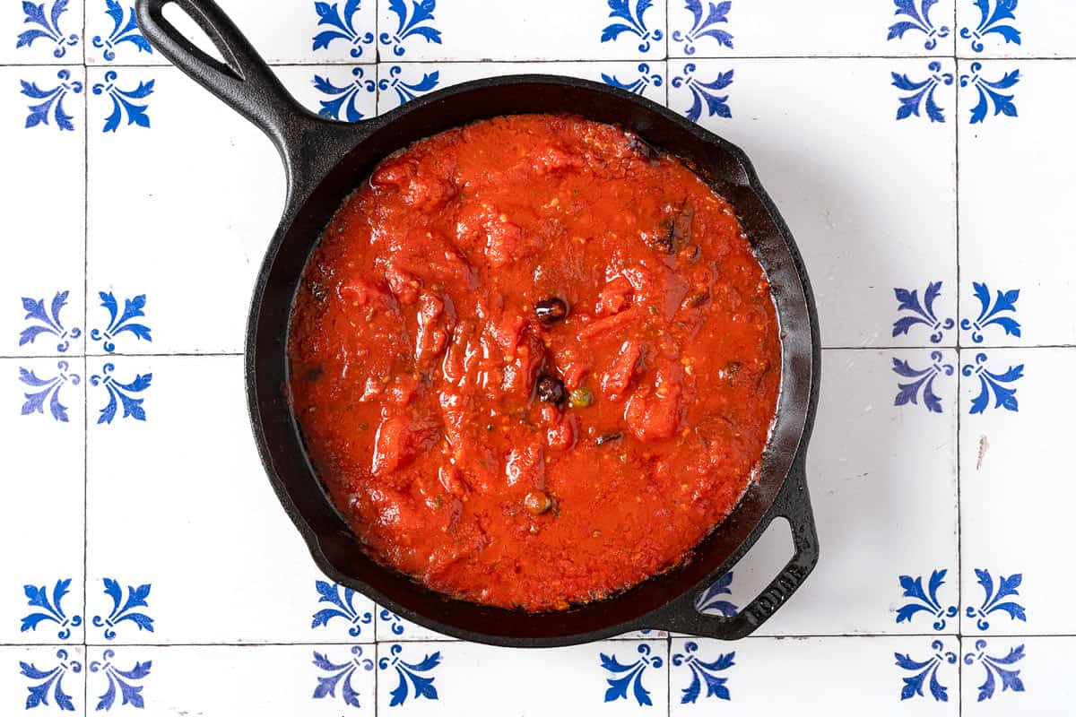 the tomato-based sauce for chicken puttanesca simmering in a skillet.