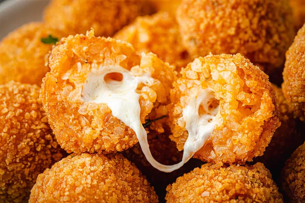 close up of an arancini ball opened up on a pile of other arancini balls.