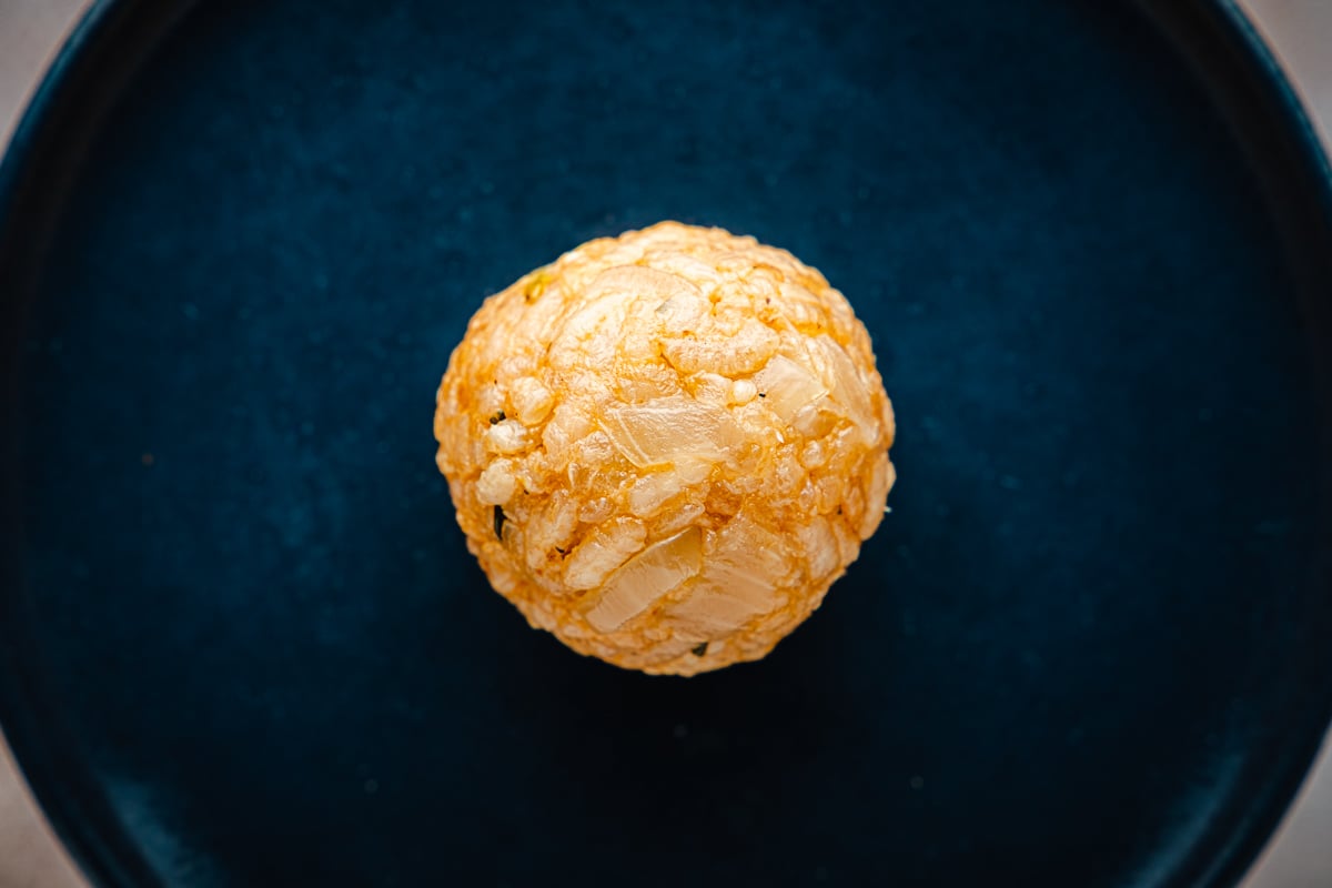 close up of an unbreaded arancini italian risotto ball on a plate.