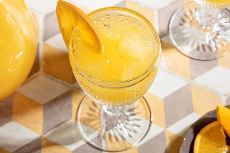 overhead shot of one glass of agua de valencia garnished with an orange slice.