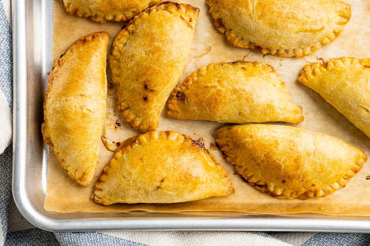 baked tuna empanadiallas on a parchment lined baking sheet.