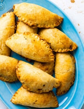 a pile of baked tuna empanadillas on a serving platter.