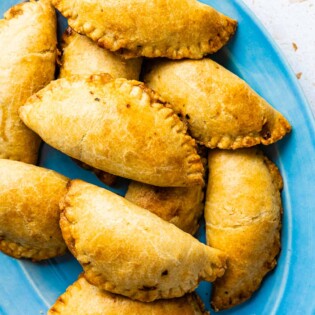 a pile of baked tuna empanadillas on a serving platter.