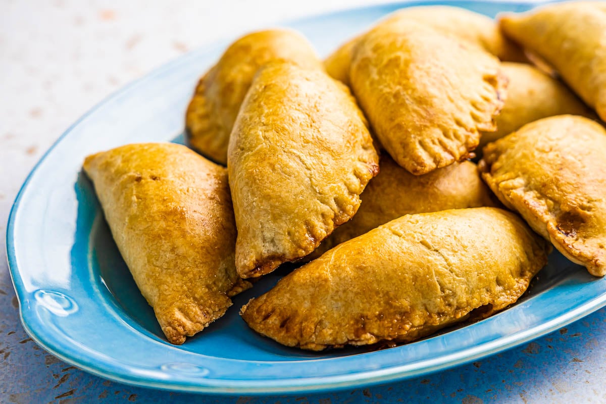 a pile of baked tuna empanadillas on a serving platter.