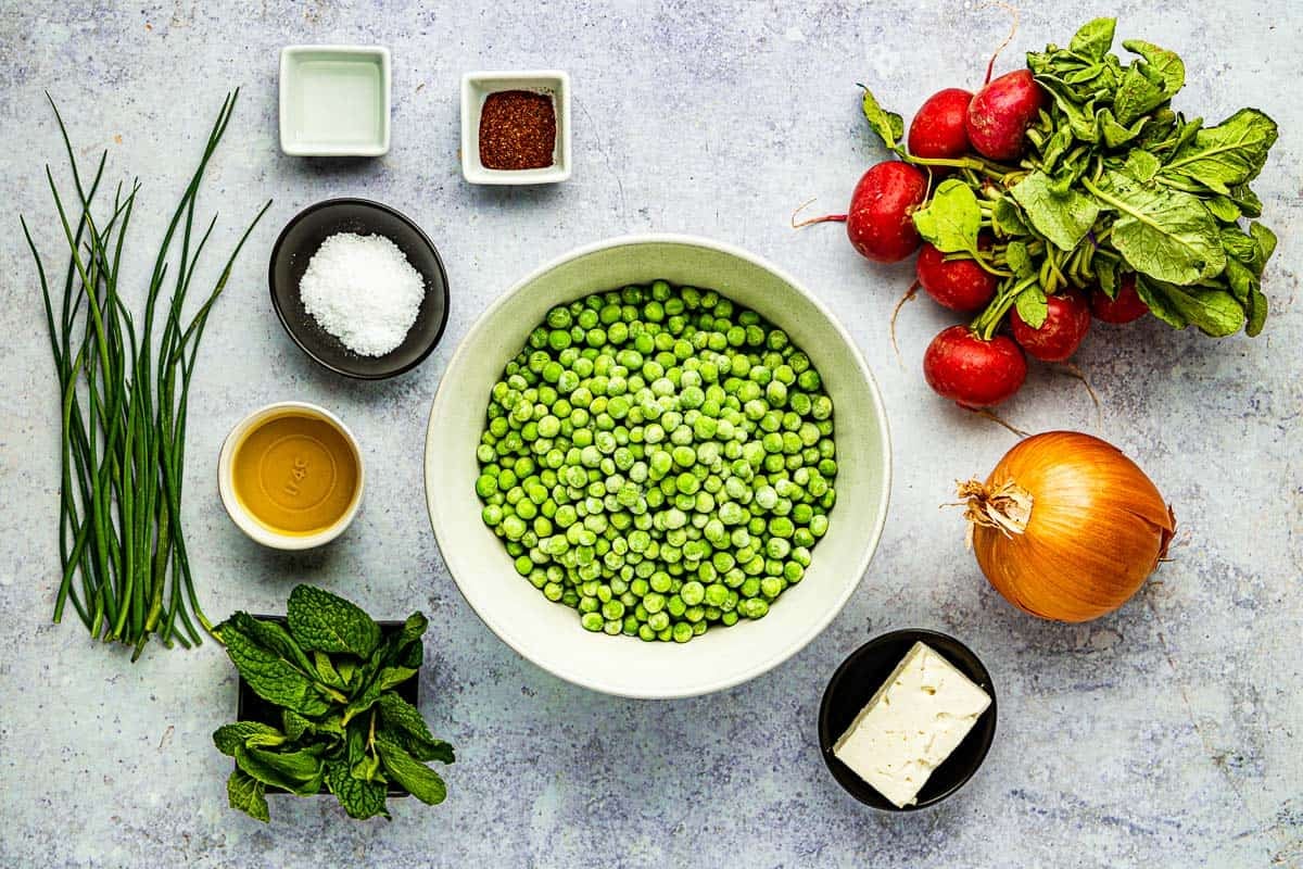 ingredients for spring pea salad including peas, radishes, mint, salt, olive oil, yellow onion, aleppo pepper, white wine vinegar, chives, and feta.