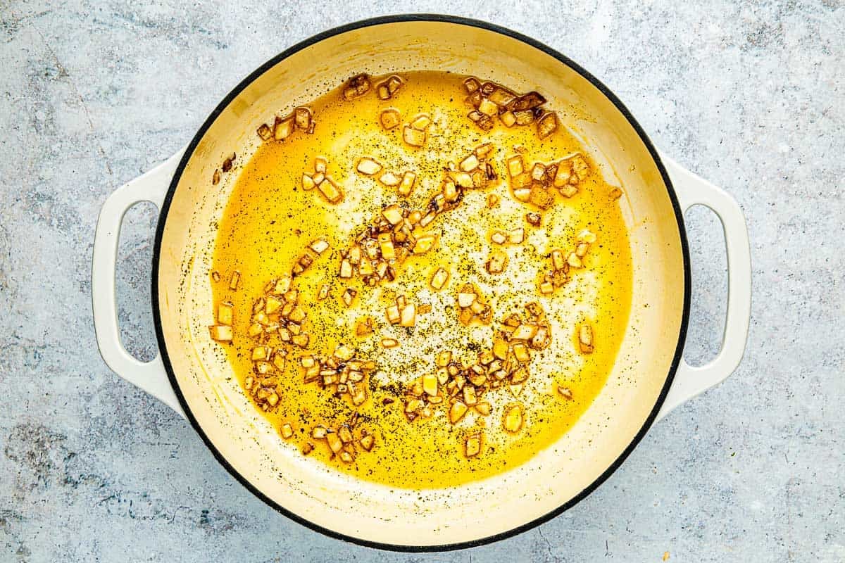 minced onion and aleppo pepper being cooked in olive oil in a pot.