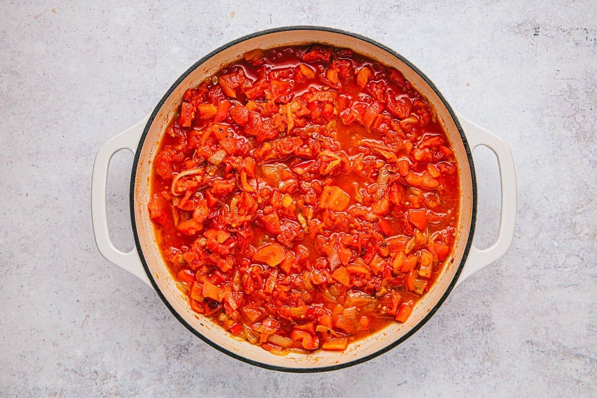 tomatoes, onions, red bell peppers, and red pepper flakes simmering in a skillet.