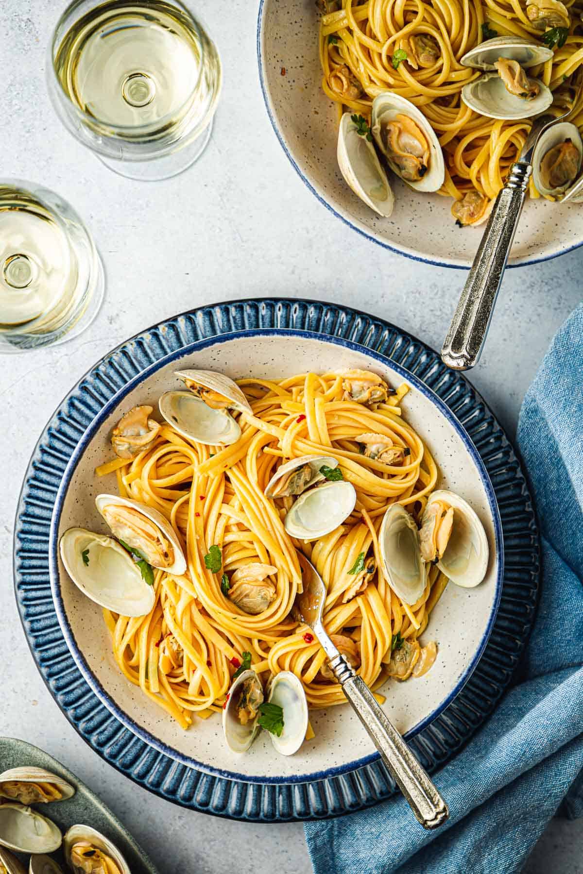 Overhead shot of linguini with clams in a blue and white serving dish.