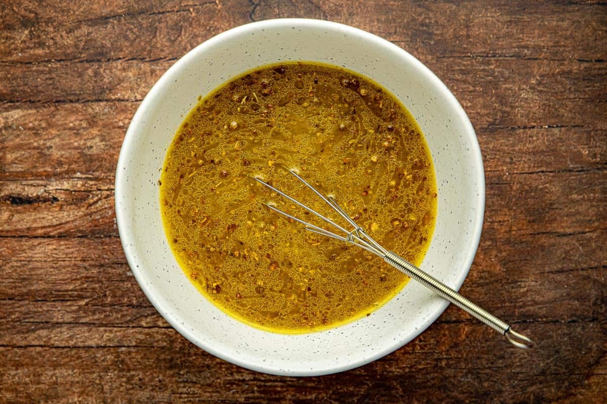 Ladolemono Greek Dressing and a whisk in a white bowl.