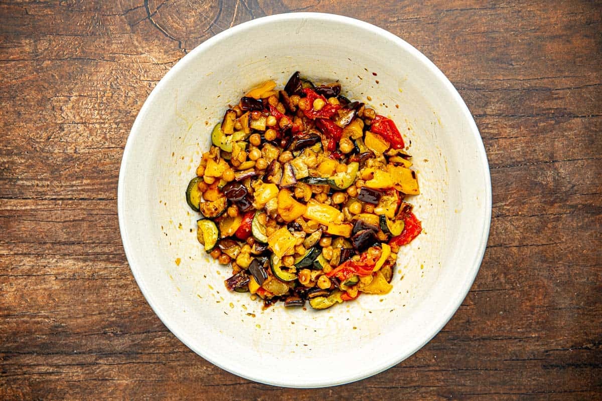 Roast vegetables in a white bowl that are ready to be dressed.