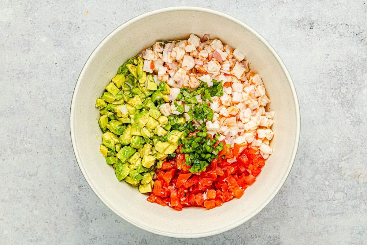 chopped shrimp, tomatoes, cilantro and avocado in a bowl.