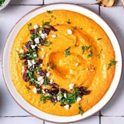 Overhead shot of Tirokafteri Spicy Greek Feta Dip with a feta, parsley, and olive garnish.