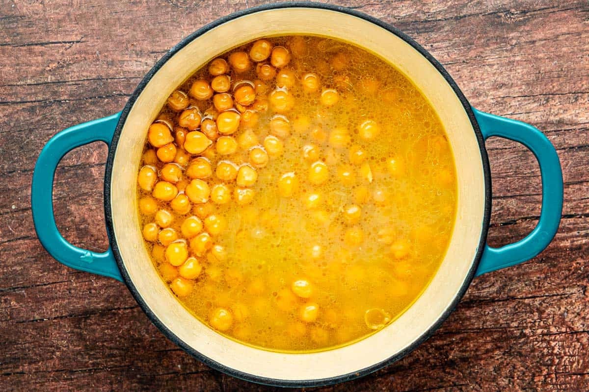 canned chickpeas simmering in their liquid in a pot.