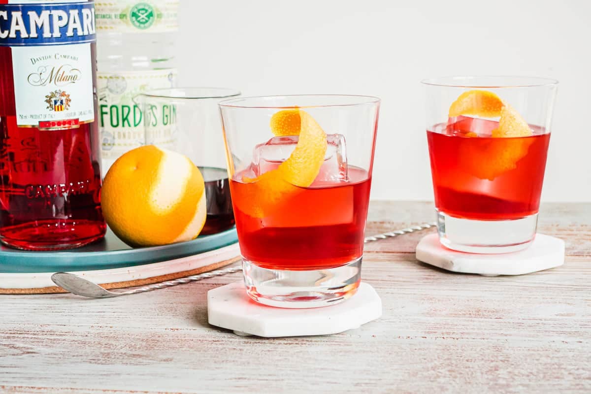 Deux cocktails negroni aux touches d'orange sur des dessous de verre en marbre.