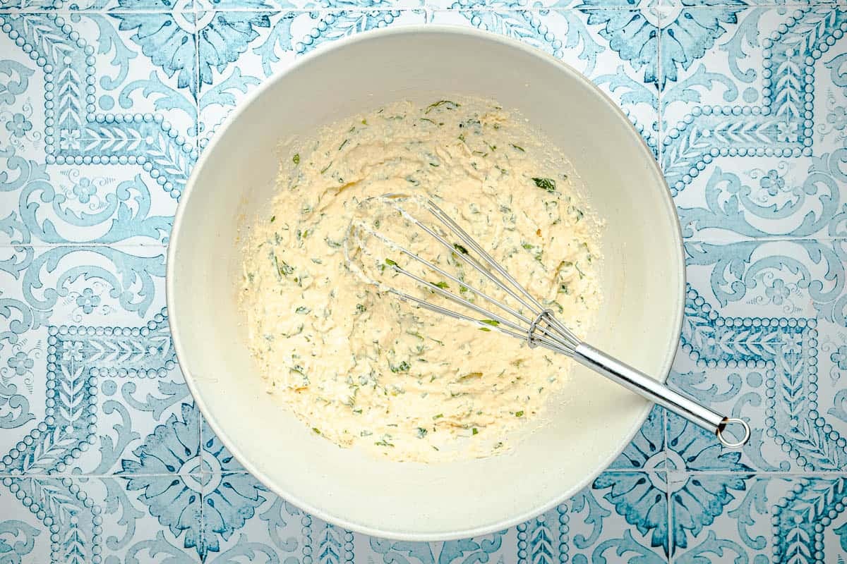 eggs, parsley, ricotta and parmesan in a mixing bowl with a whisk.