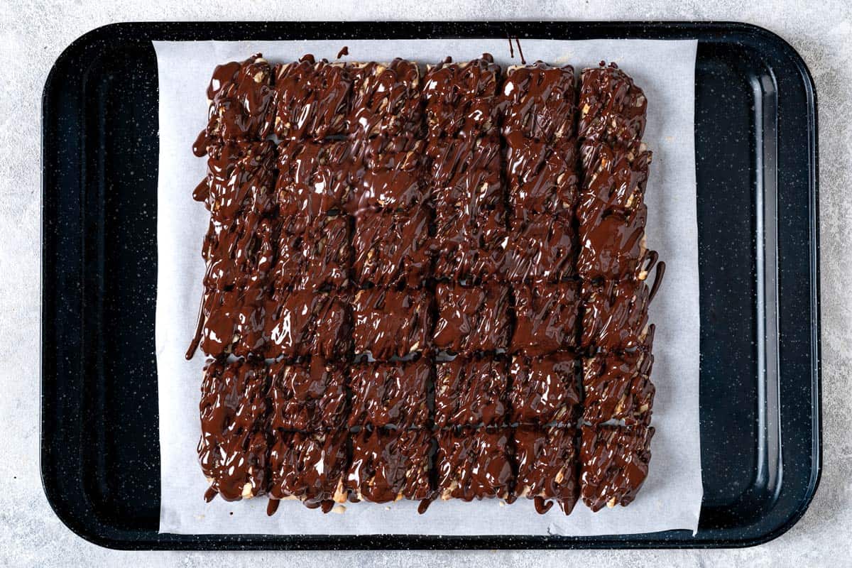 chocolate covered date bars on a parchment-lined baking sheet, pre-chilling.