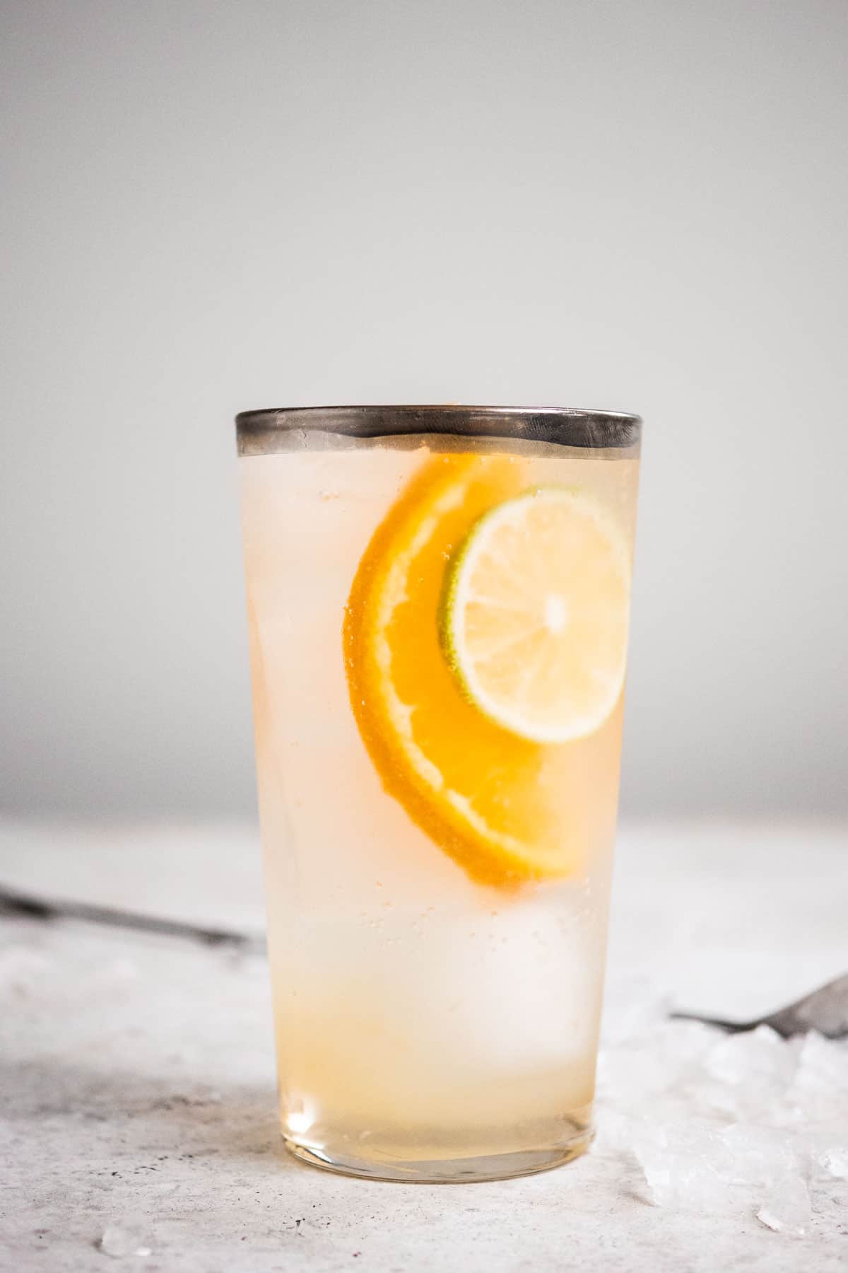 Close up of one eternal sunshine gin cocktail in a clear glass with a silver rim and a large cocktail stirrer in the background. 