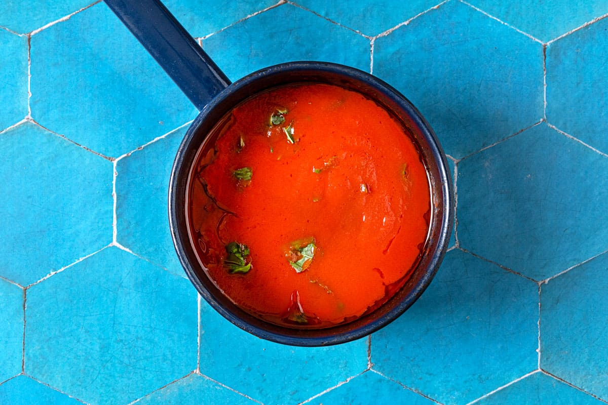 Sauce pot with oil, tomato sauce, and basil.