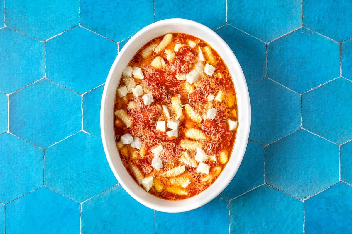 Overhead shot of gnocchi alla sorrentina, with mozzarella cheese and freshly grated Parmigiano-Reggiano on top.