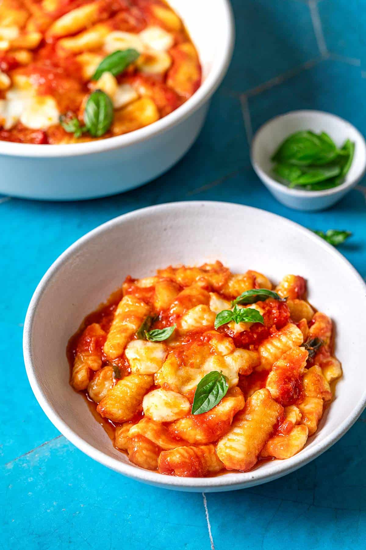 Bowl of gnocchi alla sorrentina with a fresh basil leaf garnish.