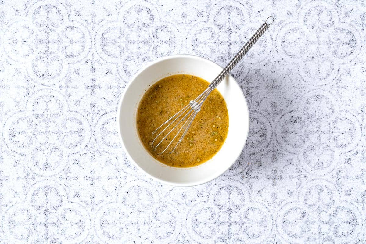 Vinaigrette for greek potato salad being whisked in a bowl.