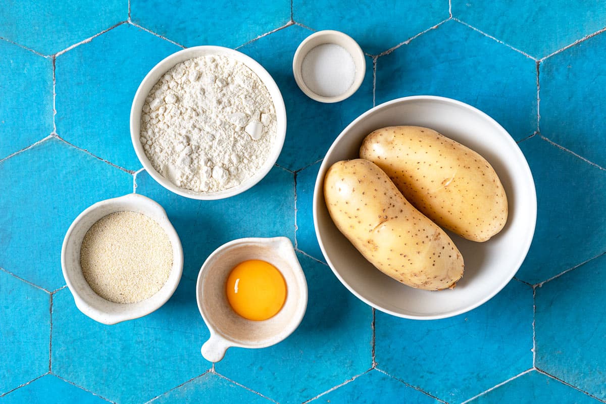 Ingredients for potato gnocchi, including egg yolk, all purpose flour, semolina flour, two potatoes, and salt.