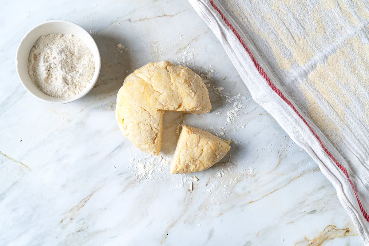 Dough for potato gnocchi with semolina flour dusted and a pie piece cut out.