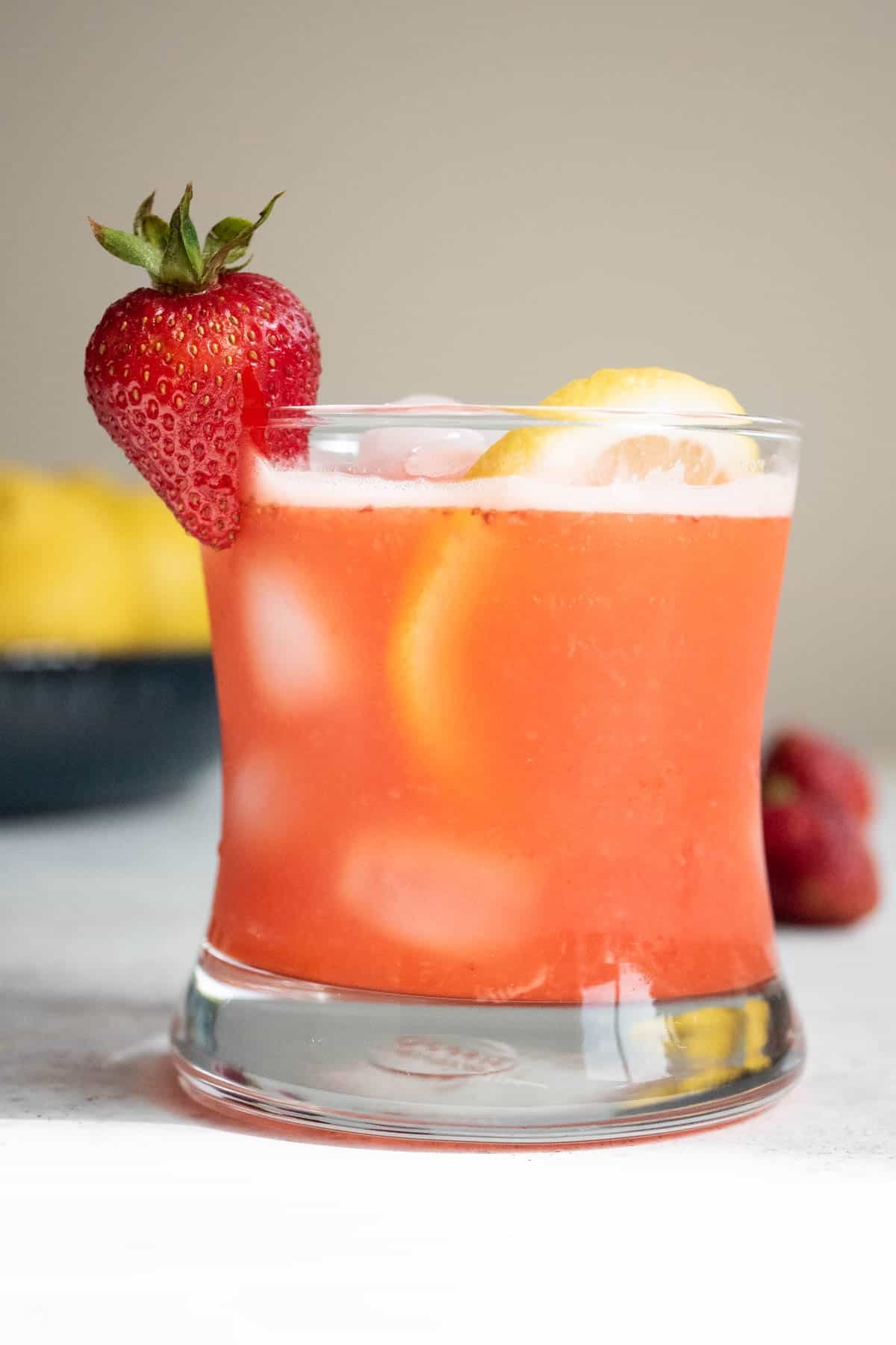 a glass of strawberry lemonade garnished with a strawberry and a lemon slice.
