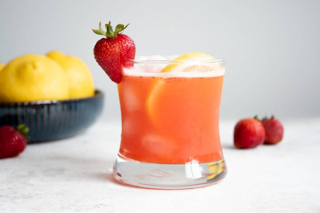 a glass of strawberry lemonade garnished with a strawberry and a lemon slice.