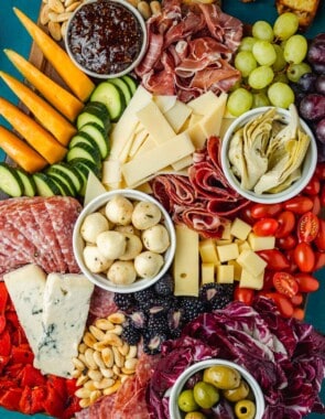 overhead photo of a large antipasto platter with a selection of meats, cheeses, fruits, vegetables and nuts.
