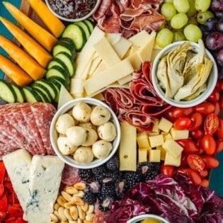 overhead photo of a large antipasto platter with a selection of meats, cheeses, fruits, vegetables and nuts.
