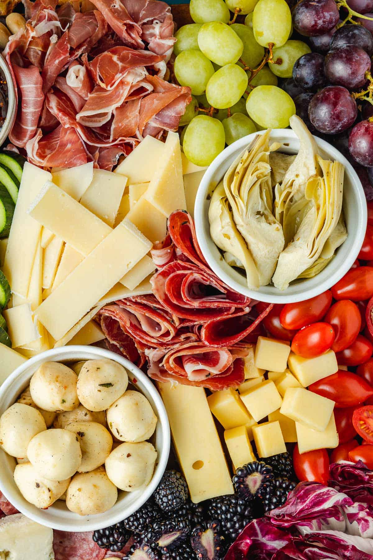 close up of a large antipasto platter with a selection of meats, cheeses, fruits, vegetables and nuts.