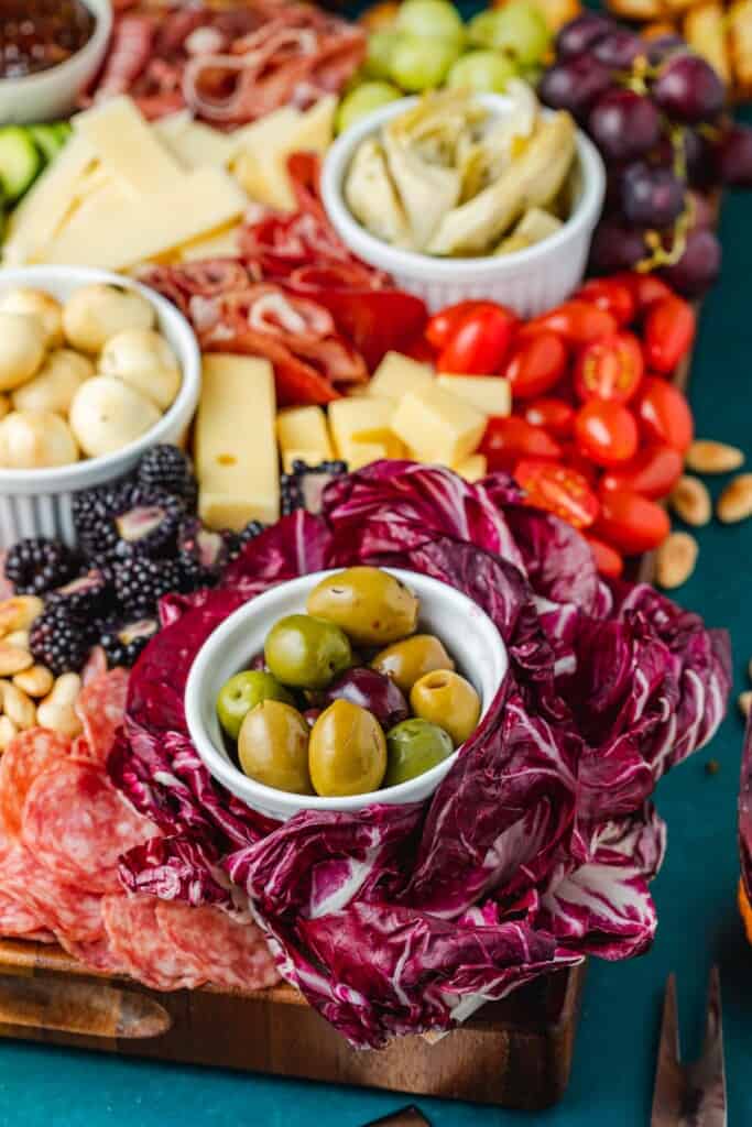 close up of a large antipasto platter with a selection of meats, cheeses, fruits, vegetables and nuts.