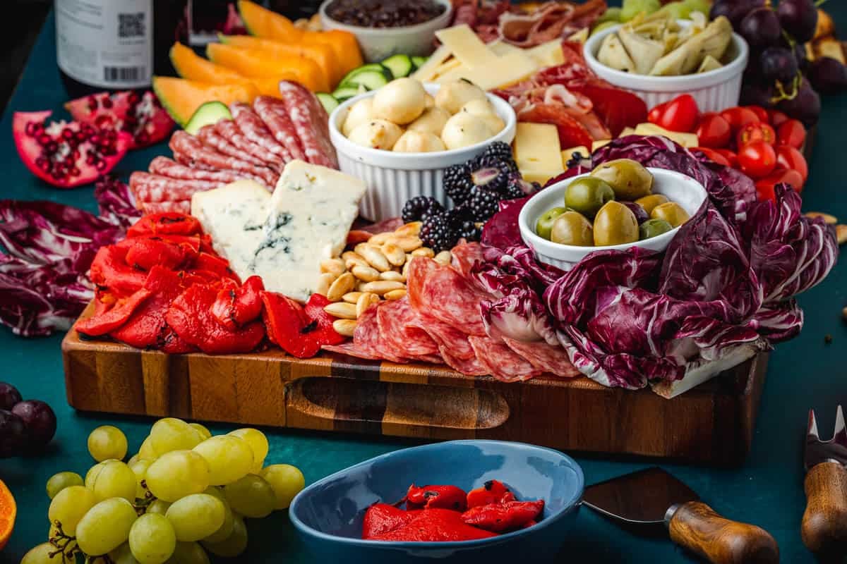 close up of a large antipasto platter with a selection of meats, cheeses, fruits, vegetables and nuts.