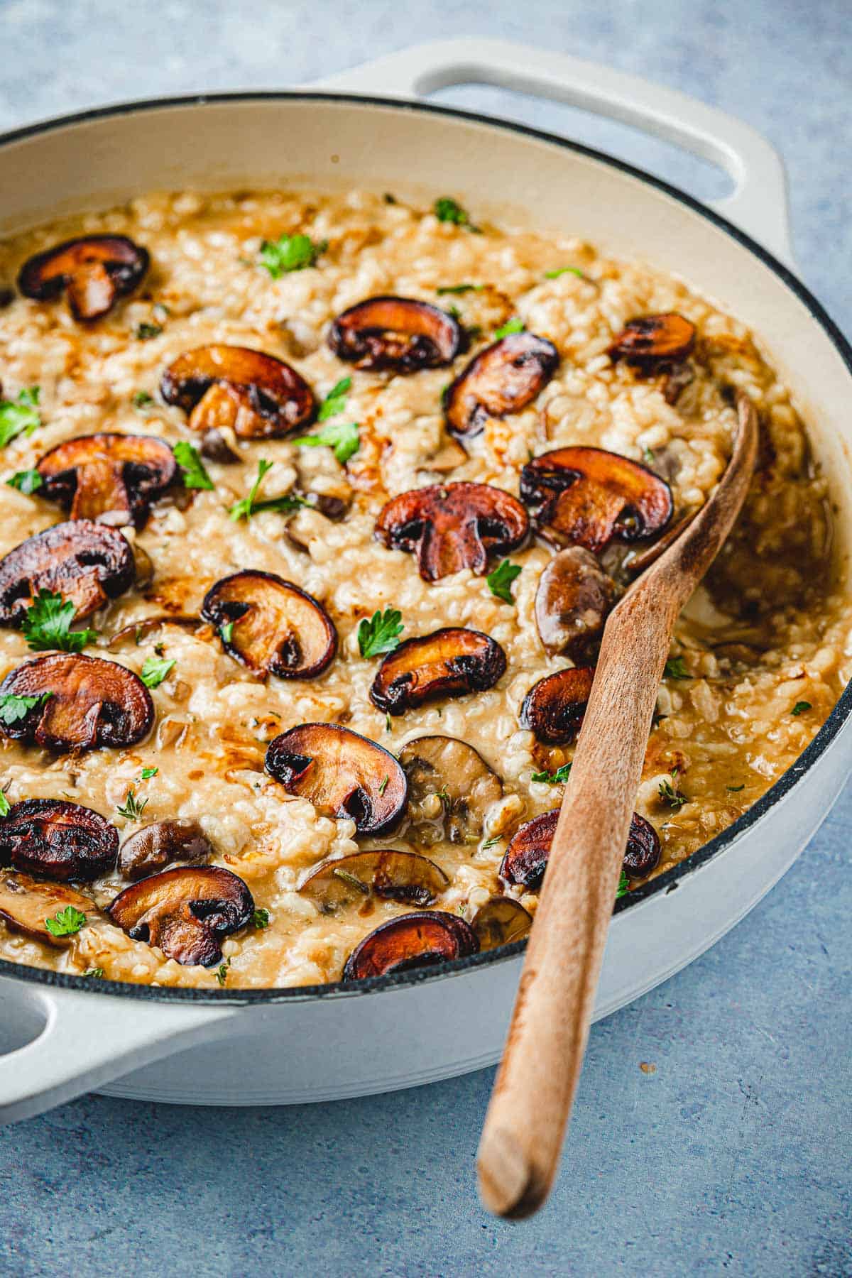 mushroom risotto in a skillet with a wooden spoon.