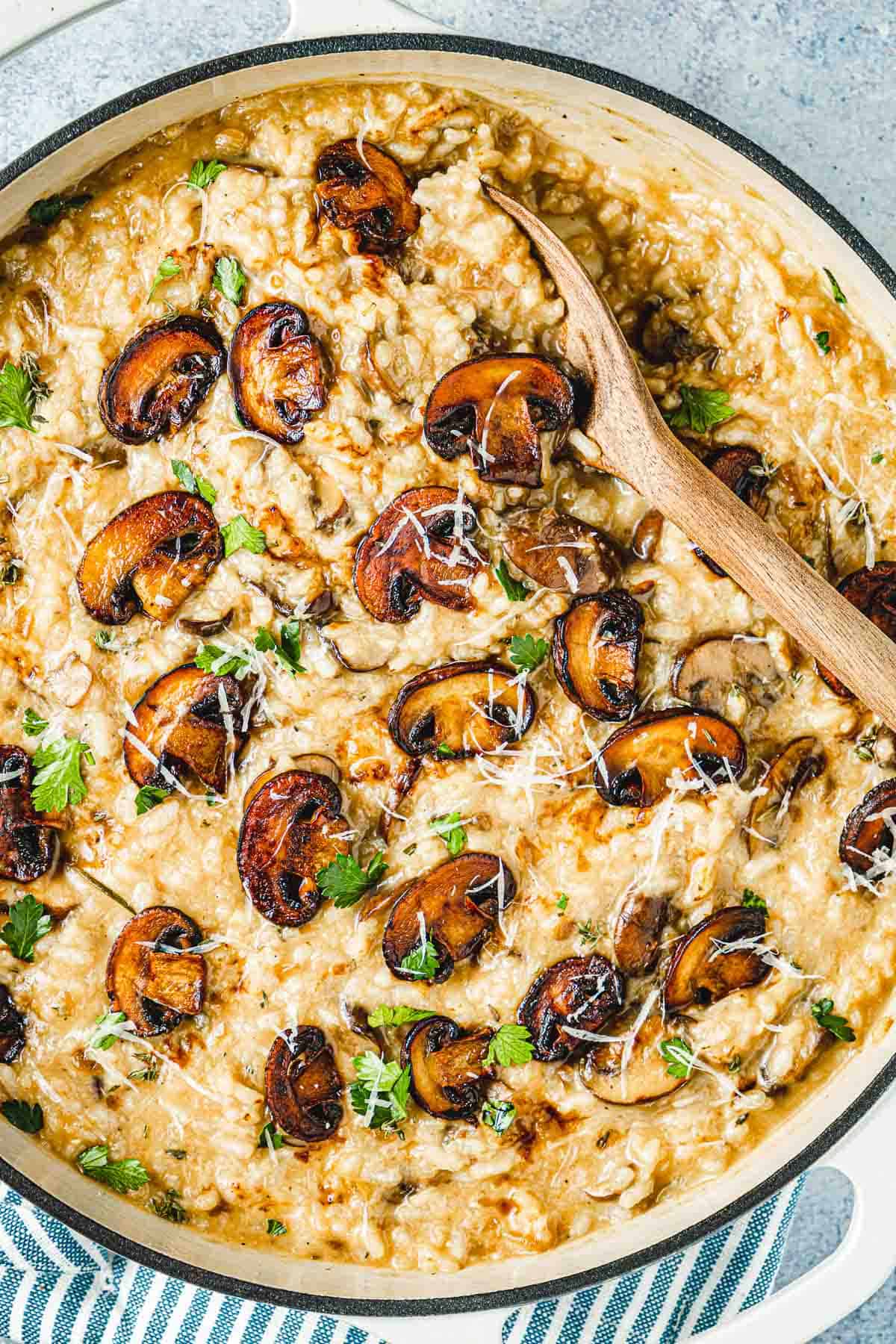 mushroom risotto in a skillet with a wooden spoon.