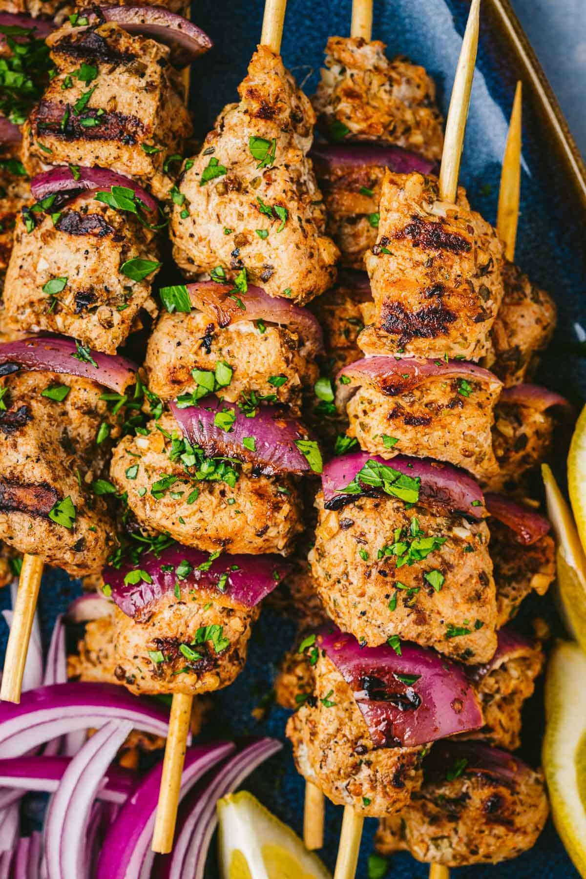 Overhead shot of pork souvlaki skewers with red onion.